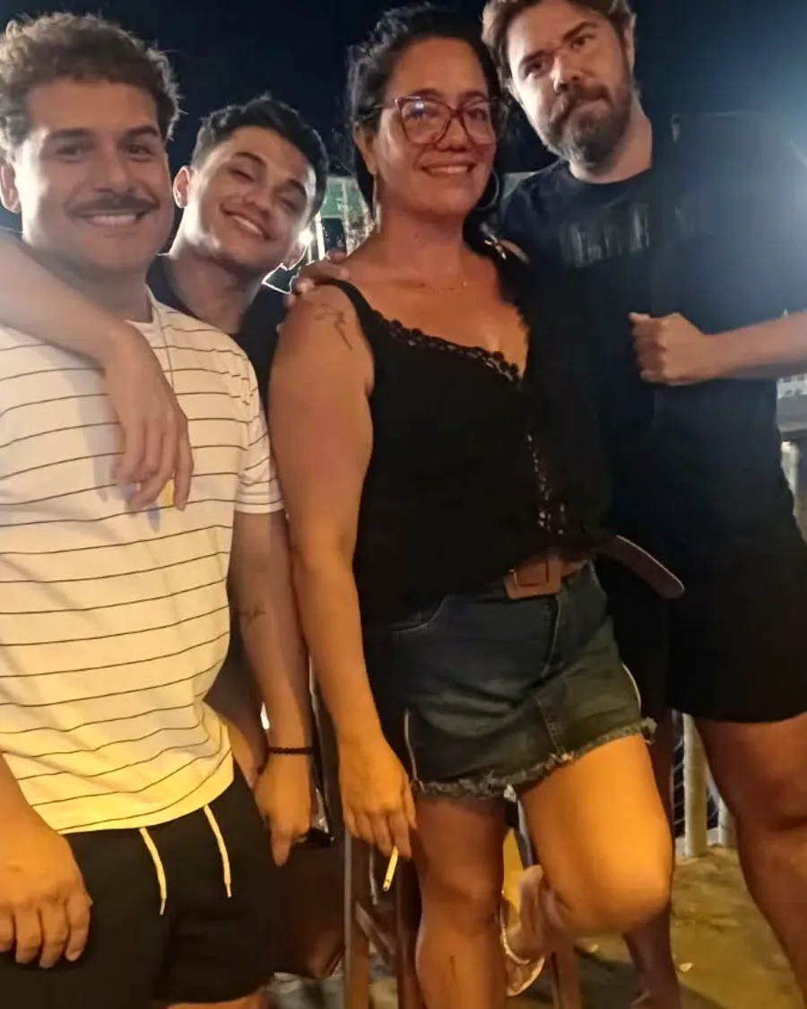 Grupo de amigos no salão do Chalé à noite, com as luzes acesas na areia