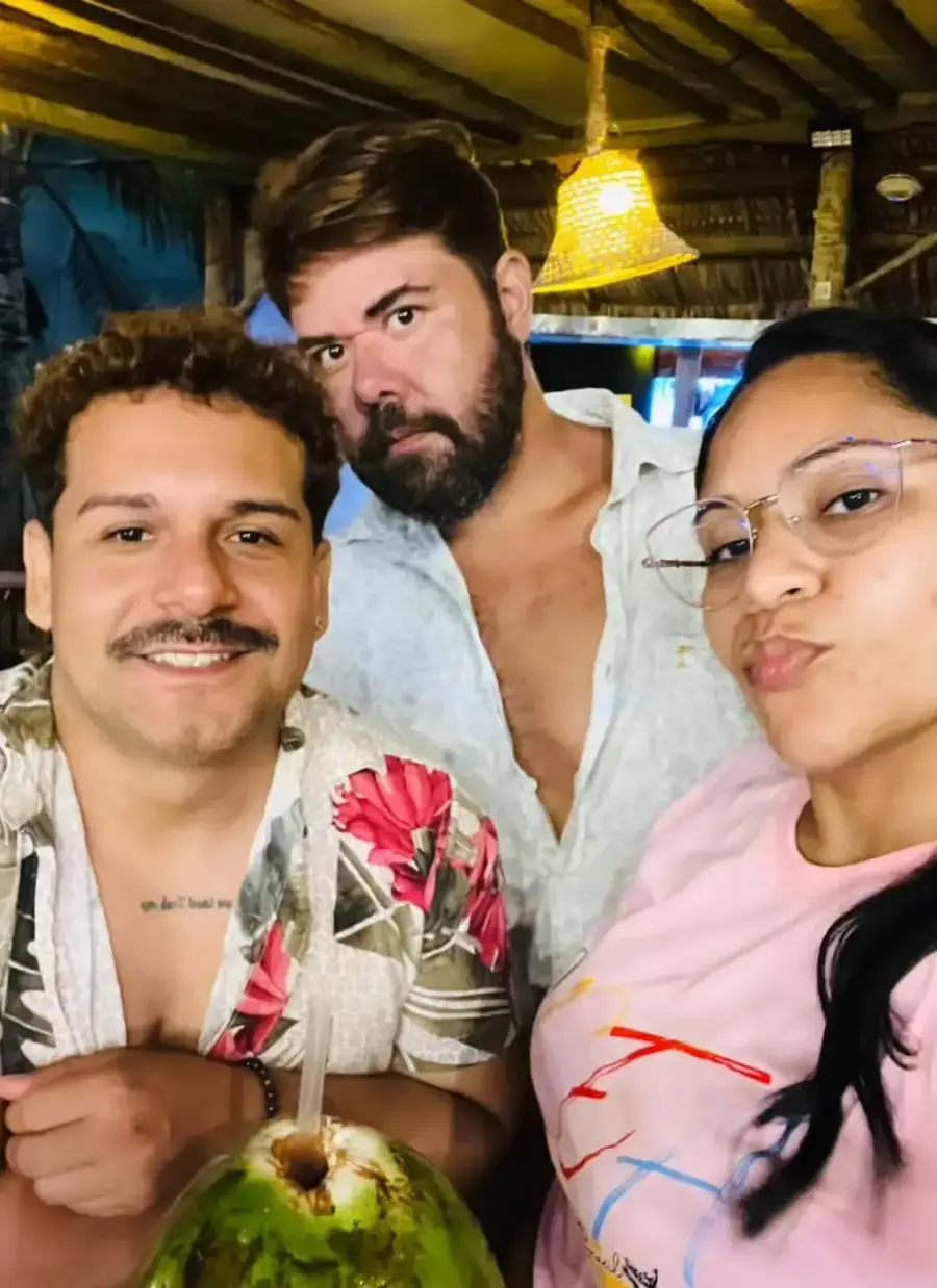 Três clientes sorrindo com um coco gelado na mesa do Chalé