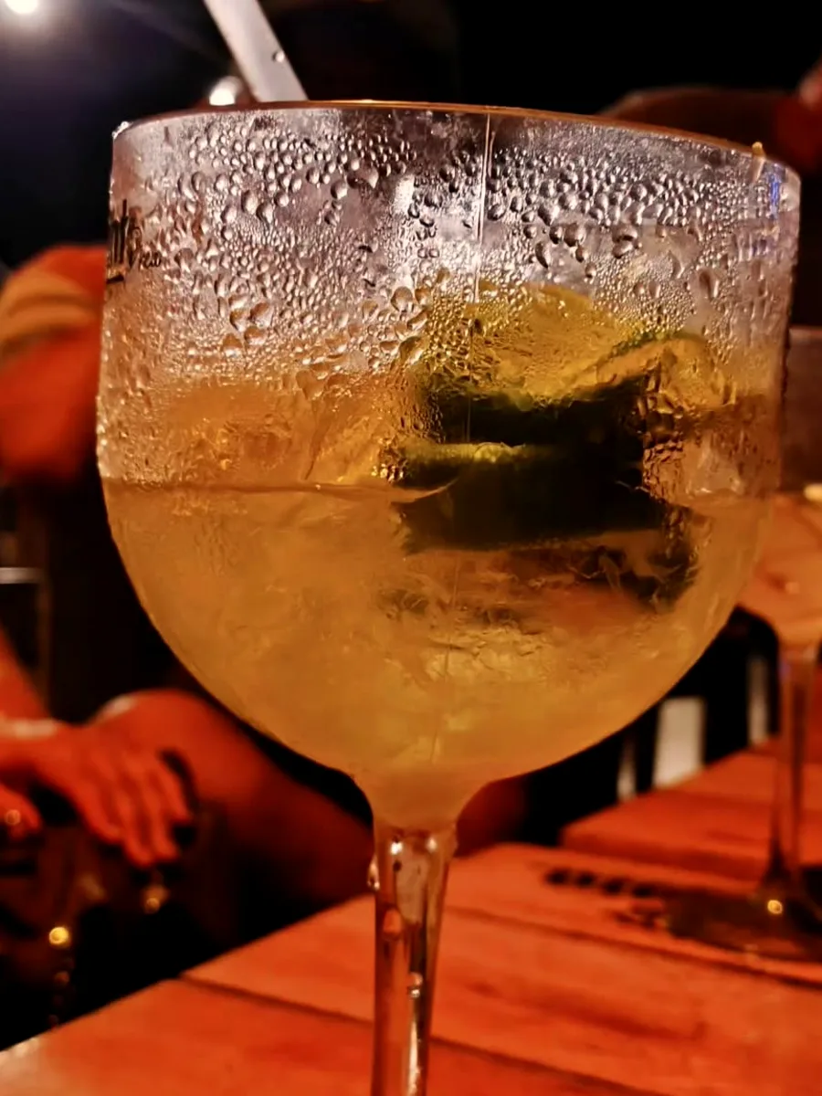 Taça de gin tônica gelada com limão sobre a mesa de madeira