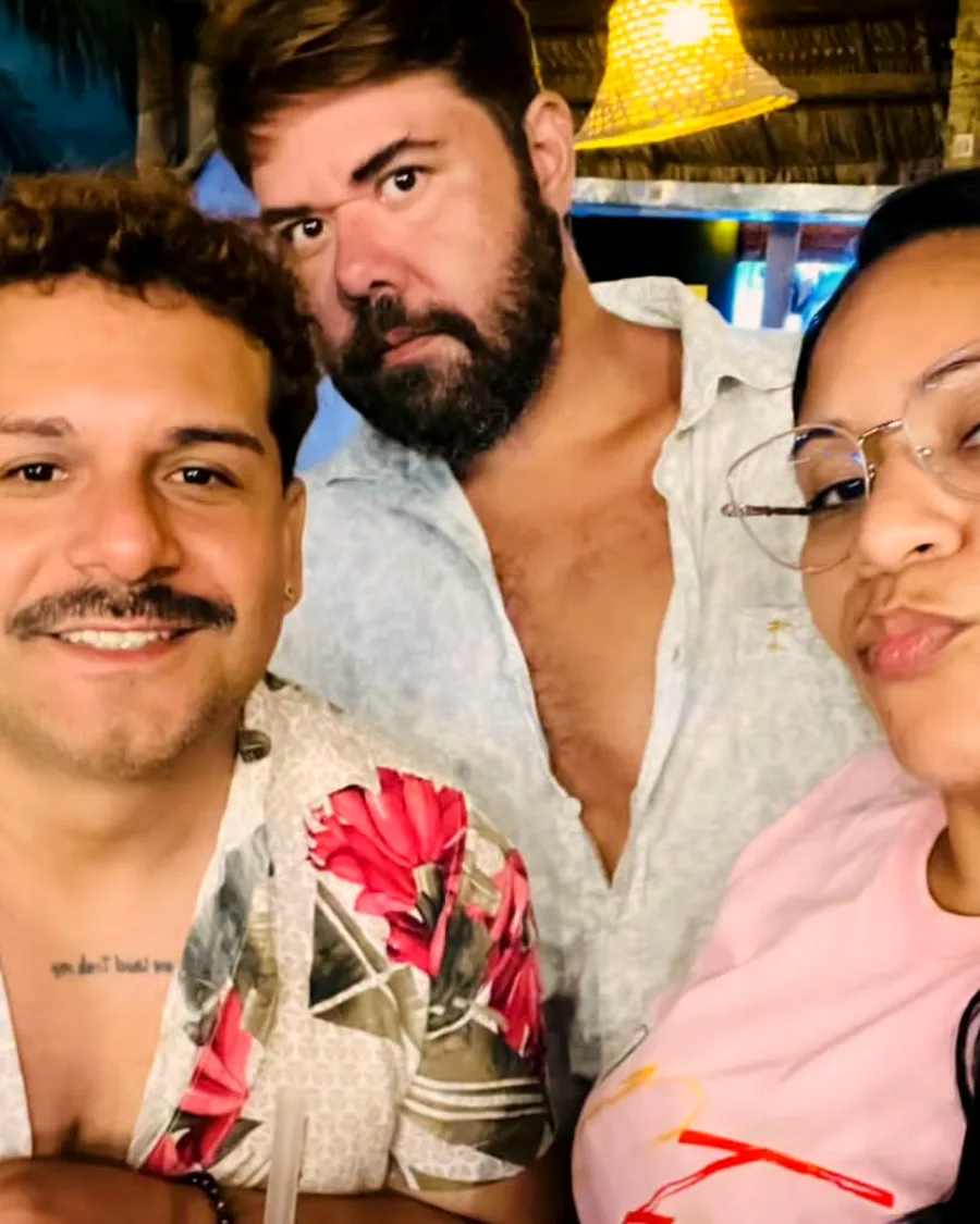 Amigos posando com um coco gelado embaixo do telhado de palha